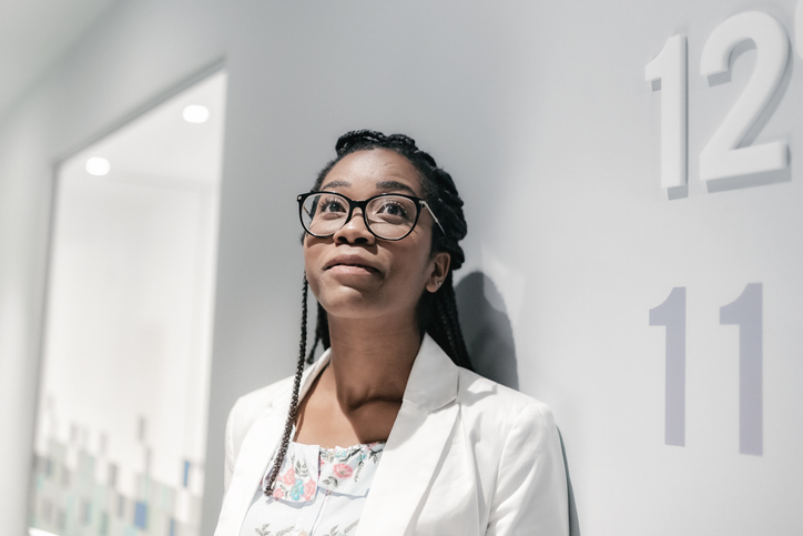 young pensive brazilian businesswoman looking up in office