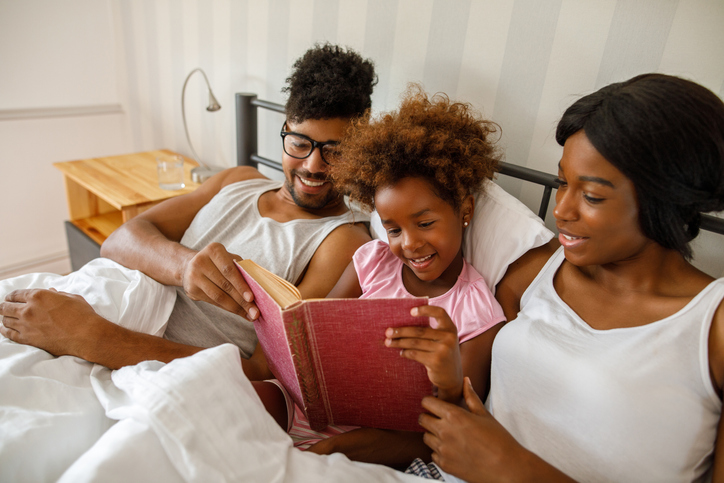 Happy family reading an interesting book in bed