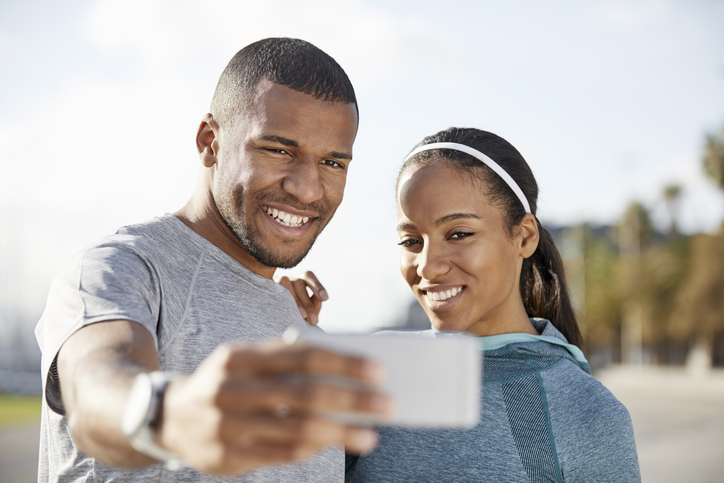 Smiling couple taking selfie at park on sunny day