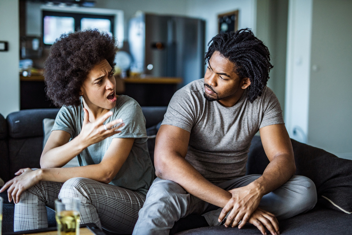 Angry African American couple arguing in the living room.