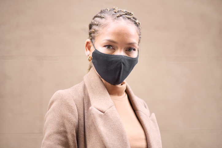 Headshot portrait of a young woman wearing a black protective face mask.