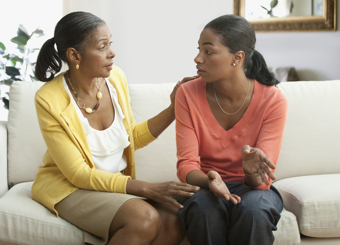 Mother and daughter talking on sofa