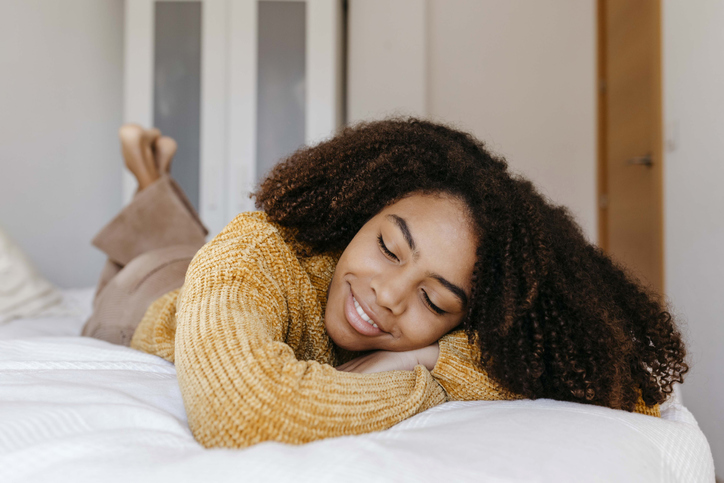 Young woman smiling while lying on bed at home