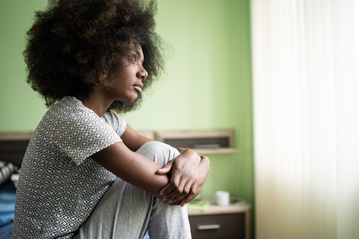 Sad afro woman sitting on a bed