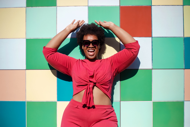 Stylish woman looking excited against multicolored tiled wall