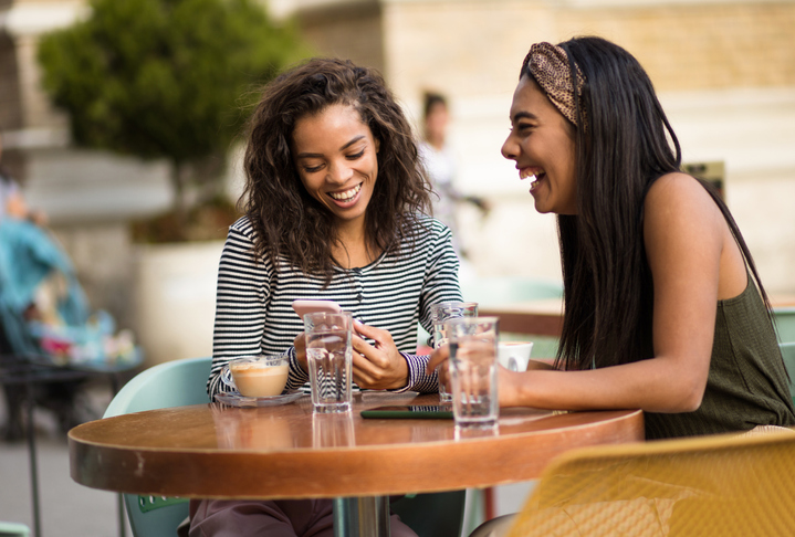 Two women in café using smart phone. Best friends.