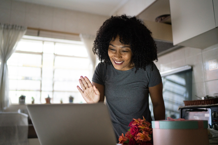 Girlfriend receiving flowers of her boyfriend and talking to him on internet via laptop at home