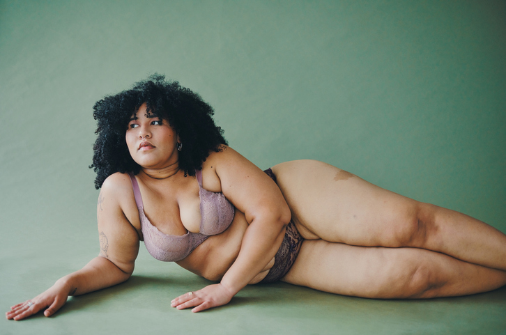 Cropped shot of an attractive and voluptuous young woman posing in her lingerie against a green background in studio