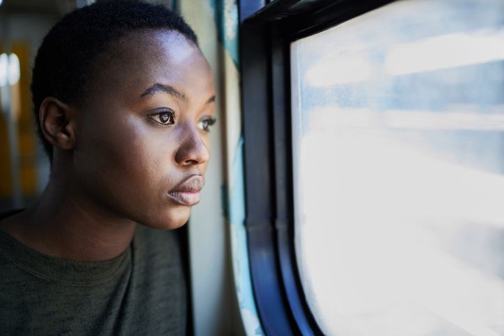 Cropped shot of a young woman looking depressed while staring out the window of a train