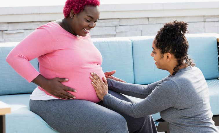 Pregnant woman with doula touching baby bump